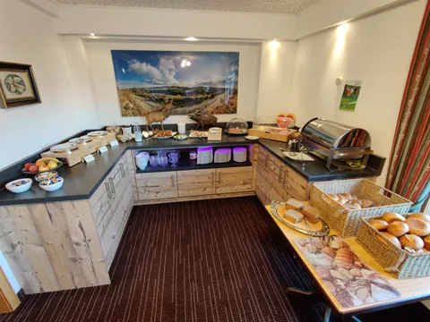 Frühstücksbuffet mit Bergpanorama-Bild an der Wand