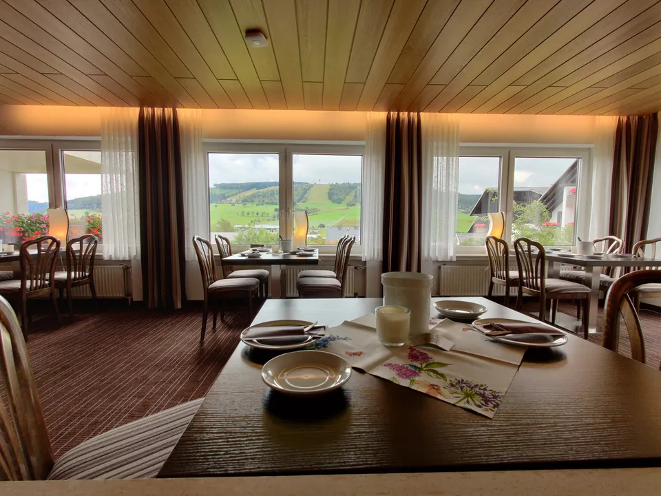 Gedeckter Tisch im Frühstücksraum vor dem Panoramafenster