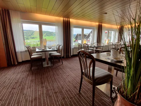 Frühstücksraum mit großen Fenstern und Blick ins Grüne