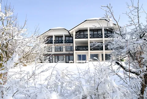 Der Magdalenenhof im Schnee unter blauem Himmel