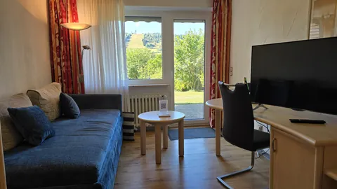 Komfort-Doppelzimmer mit Terrasse: Sofa, Schreibtisch und Tür zur Terrasse